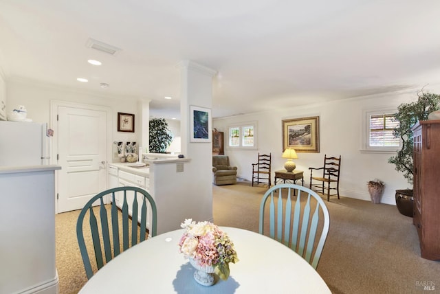 dining room with light colored carpet and crown molding