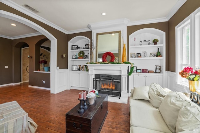 living room featuring built in features, dark hardwood / wood-style flooring, and crown molding