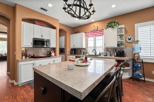 kitchen featuring backsplash, a kitchen island, dark wood-type flooring, and a notable chandelier