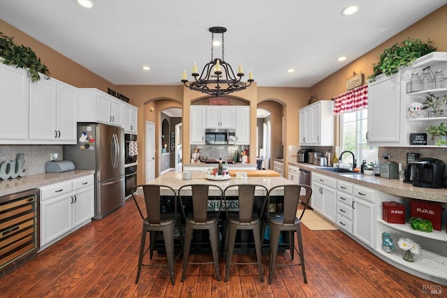 kitchen featuring wine cooler, white cabinets, stainless steel appliances, decorative light fixtures, and dark hardwood / wood-style flooring