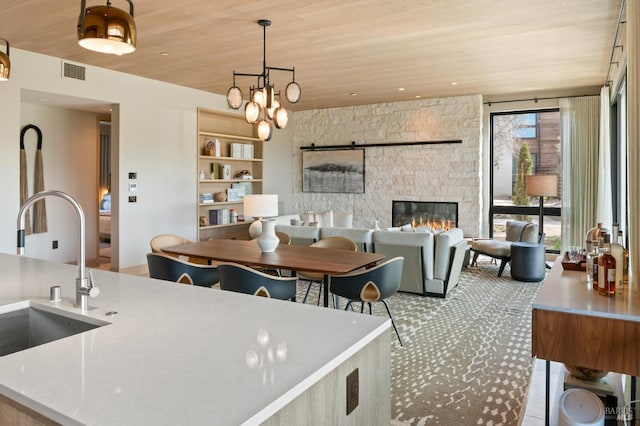 kitchen with light countertops, decorative light fixtures, wooden ceiling, a sink, and visible vents