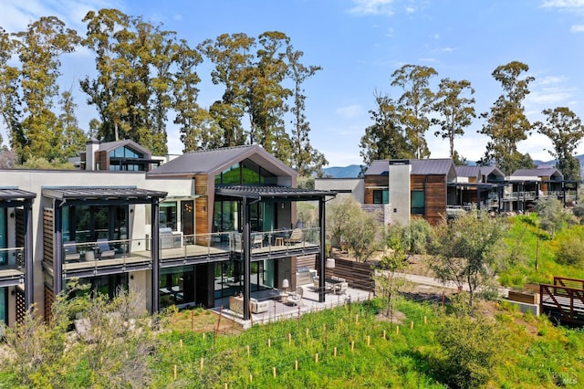 rear view of property with a balcony, a pergola, and a patio