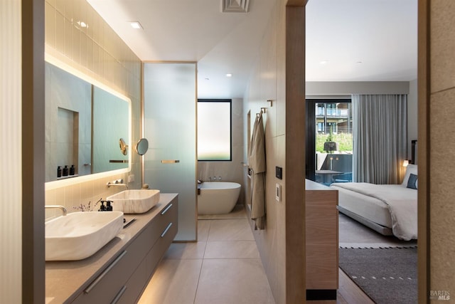 bathroom featuring ensuite bathroom, a freestanding bath, tile patterned flooring, and a sink