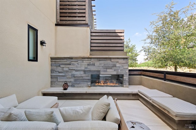 view of patio / terrace with an outdoor living space with a fireplace and a balcony