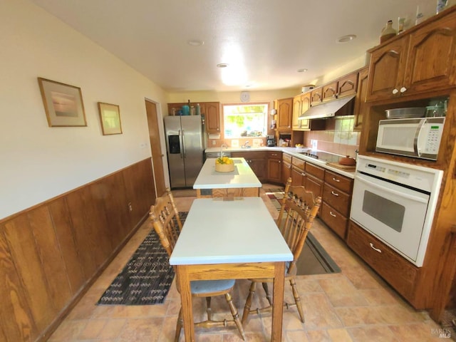 kitchen featuring wooden walls, backsplash, appliances with stainless steel finishes, and a kitchen island