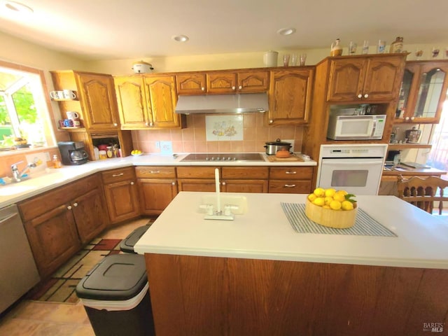 kitchen featuring decorative backsplash, white appliances, a center island, and sink