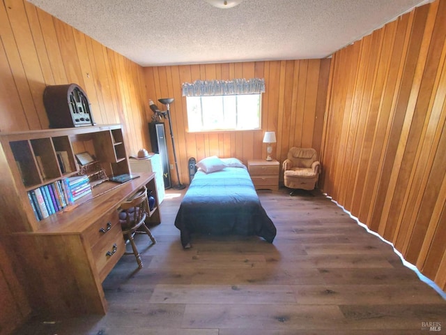 bedroom featuring a textured ceiling, wood walls, and dark wood-type flooring