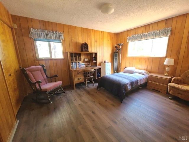 bedroom featuring a textured ceiling, wooden walls, and dark hardwood / wood-style flooring