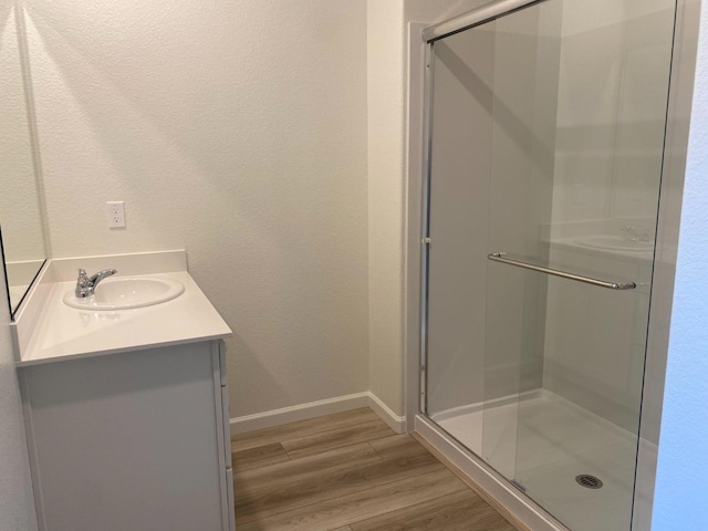 bathroom with hardwood / wood-style flooring, vanity, and a shower with door