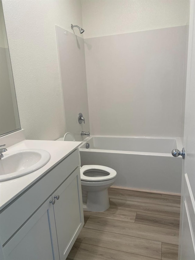 full bathroom with washtub / shower combination, vanity, toilet, and hardwood / wood-style floors