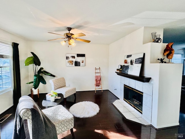 living room featuring a tile fireplace, ceiling fan, and wood-type flooring