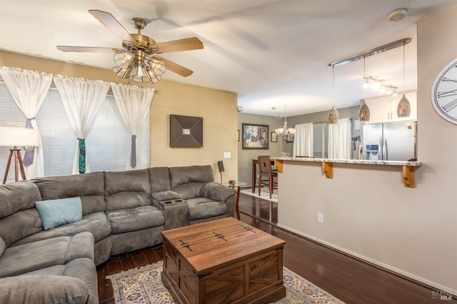 living room featuring dark wood-type flooring and ceiling fan with notable chandelier