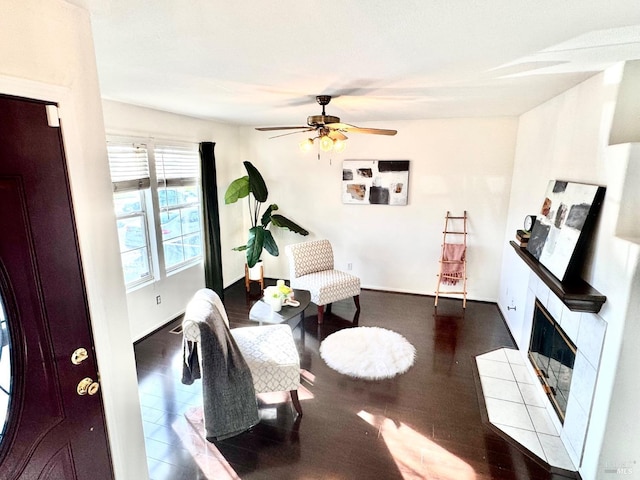 sitting room with a tile fireplace, hardwood / wood-style flooring, and ceiling fan