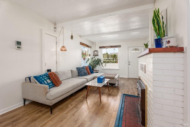 living room featuring beamed ceiling, hardwood / wood-style flooring, and a fireplace