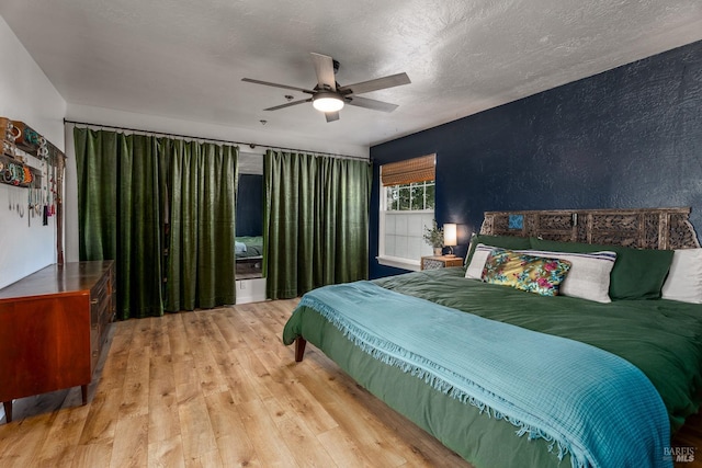 bedroom with a textured ceiling, light hardwood / wood-style floors, and ceiling fan