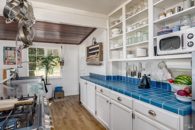 kitchen featuring white cabinetry, tile countertops, wooden ceiling, lofted ceiling, and light hardwood / wood-style flooring