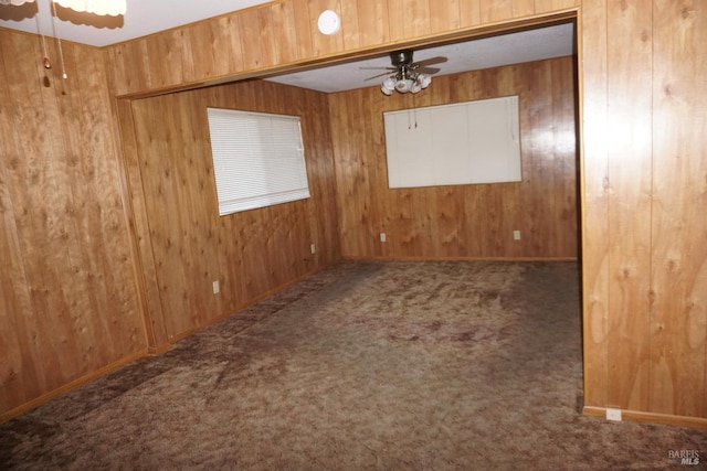 unfurnished room with ceiling fan, wood walls, and carpet flooring