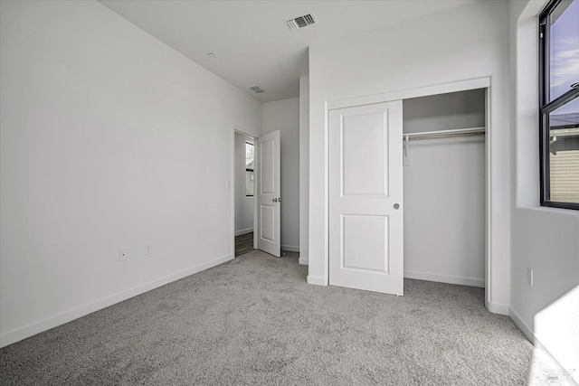 unfurnished bedroom with multiple windows, light carpet, and a closet