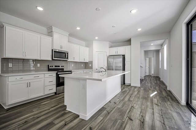 kitchen with white cabinetry, sink, dark hardwood / wood-style flooring, stainless steel appliances, and a center island with sink