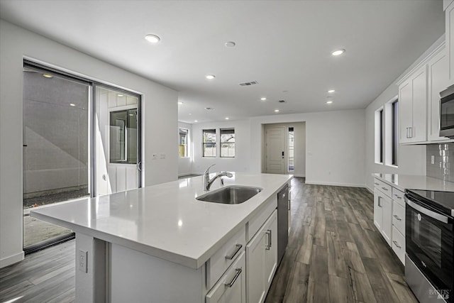 kitchen with sink, white cabinetry, appliances with stainless steel finishes, an island with sink, and hardwood / wood-style floors