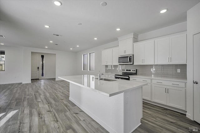 8953 Camino Colegio Rd, Rohnert Park, CA 94928 - kitchen featuring appliances with stainless steel finishes, a sink, decorative backsplash, wood finished floors, and a center island with sink