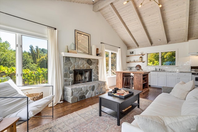 living room with high vaulted ceiling, wood-type flooring, beam ceiling, and a stone fireplace