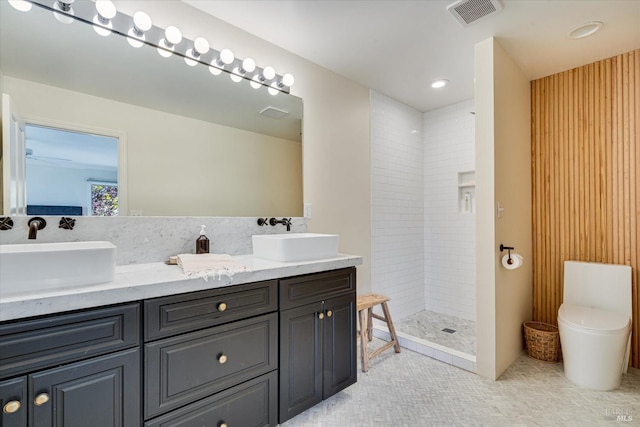 bathroom featuring vanity, a tile shower, and toilet