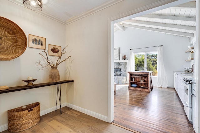 corridor featuring lofted ceiling with beams, light wood-type flooring, and crown molding