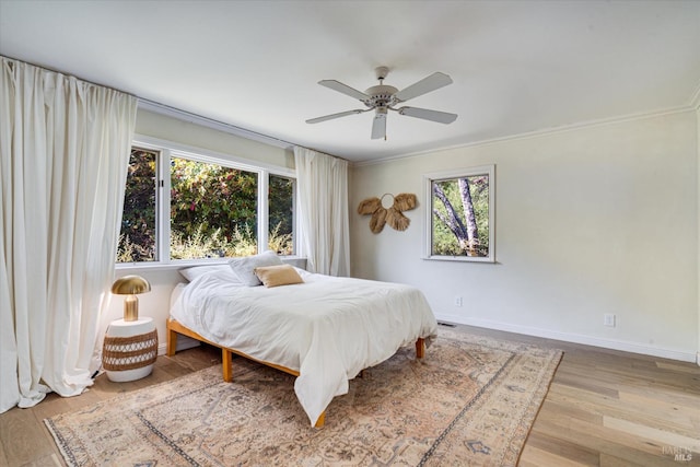 bedroom featuring multiple windows, crown molding, ceiling fan, and light hardwood / wood-style flooring