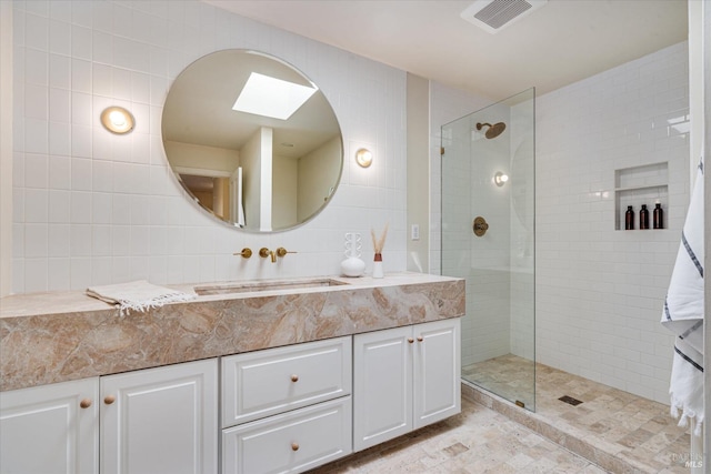 bathroom with a tile shower, tile walls, vanity, and tasteful backsplash