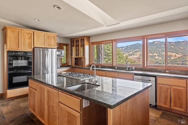 kitchen featuring dark stone countertops, a center island, appliances with stainless steel finishes, and sink