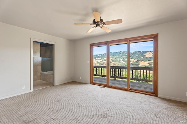 carpeted empty room with ceiling fan and a mountain view