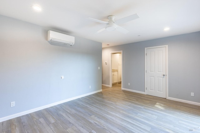 unfurnished bedroom with an AC wall unit, light hardwood / wood-style floors, and ceiling fan