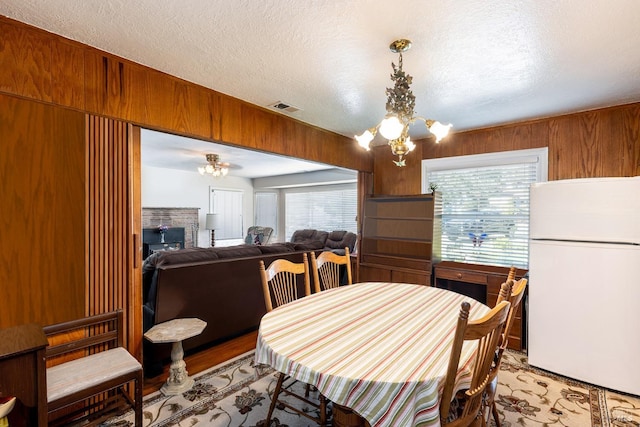 dining area featuring a textured ceiling, wooden walls, a chandelier, and a wealth of natural light