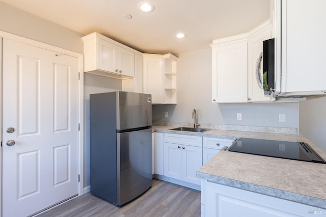 kitchen with light hardwood / wood-style flooring, stainless steel appliances, sink, and white cabinetry