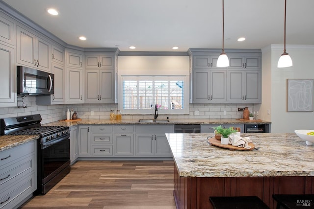 kitchen with hanging light fixtures, ornamental molding, sink, black appliances, and decorative backsplash