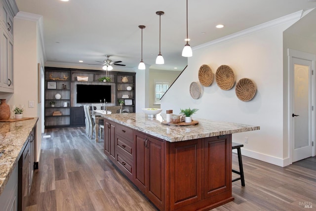 kitchen with hanging light fixtures, dark hardwood / wood-style floors, ceiling fan, and a breakfast bar