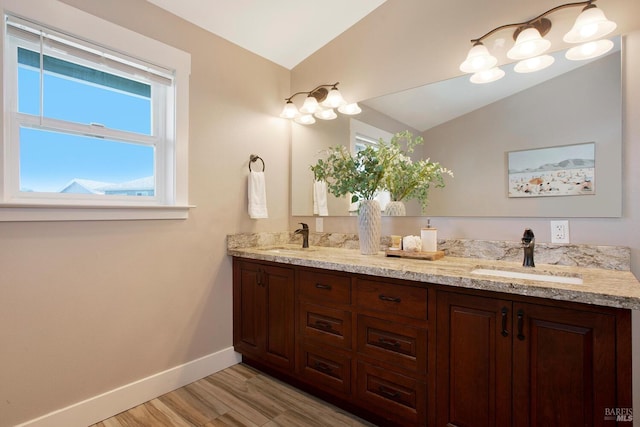 bathroom with wood-type flooring, vaulted ceiling, and vanity