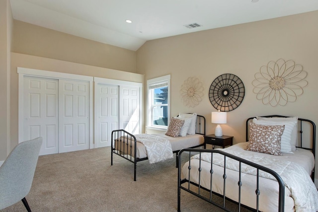 carpeted bedroom featuring two closets and lofted ceiling