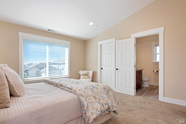 carpeted bedroom featuring ensuite bath and vaulted ceiling