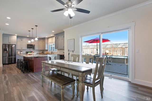 dining room featuring crown molding, dark hardwood / wood-style flooring, ceiling fan, and a wealth of natural light