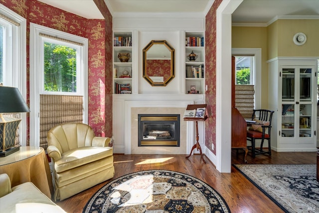 living room with ornamental molding, built in shelves, and dark wood-type flooring