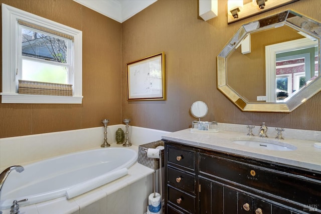 bathroom featuring vanity, tiled bath, and a wealth of natural light