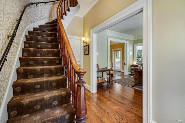 stairway with crown molding and hardwood / wood-style floors