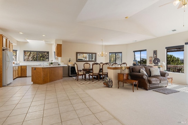 living room featuring light carpet, ceiling fan with notable chandelier, lofted ceiling, and a healthy amount of sunlight