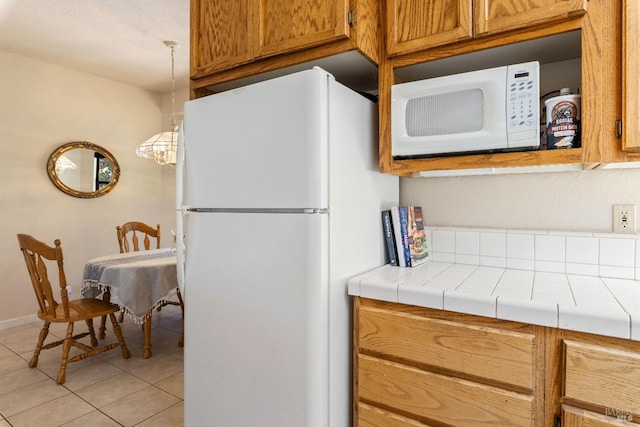 kitchen featuring white appliances, light tile patterned floors, tile countertops, and decorative light fixtures