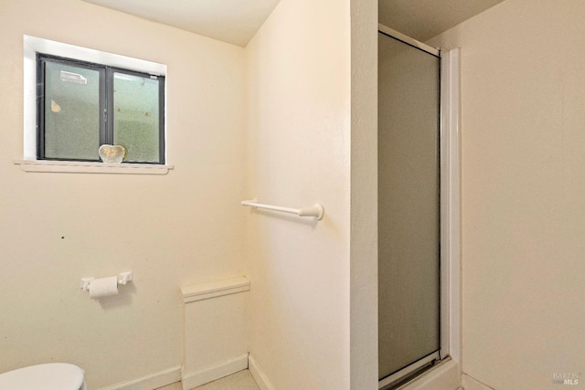 bathroom featuring a shower with door and toilet