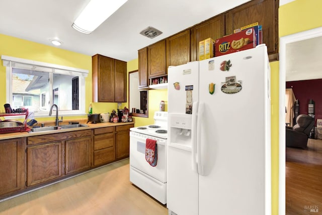 kitchen with light wood-type flooring, white appliances, and sink