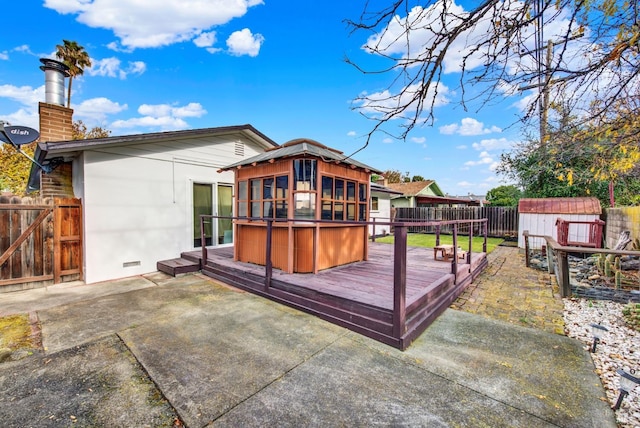 back of house featuring a deck, a hot tub, a patio area, a sunroom, and a shed