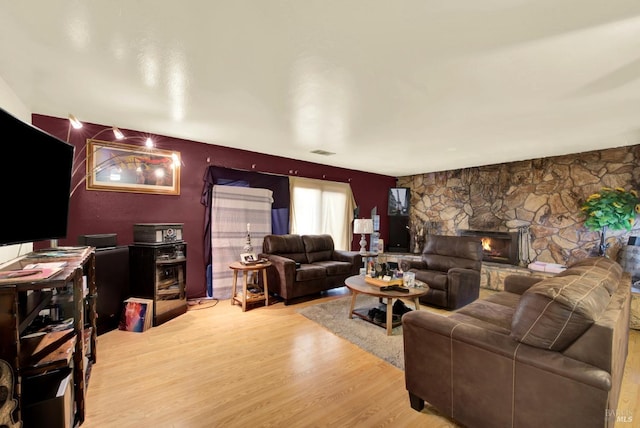 living room featuring a stone fireplace and hardwood / wood-style flooring